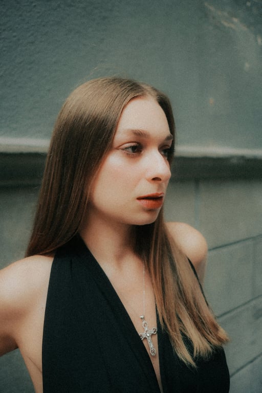 Extend the original image of the person into a complete full-body view while preserving the same individual, facial identity, clothing, and studio environment. Reconstruct the missing lower body with natural human proportions, relaxed upright posture, balanced anatomy, and lighting that matches the original image so the result appears as a single uninterrupted full-body photo.