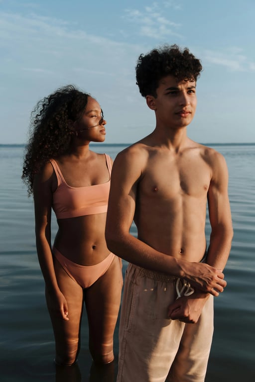 a portrait of a couple transformed to wear different bathing suits than the original, visibly altering swimsuit coverage, neckline depth, side exposure, and bottom shape for each person, while maintaining realistic fabric behavior, smooth seams, correct anatomy, natural pose, and clean lighting