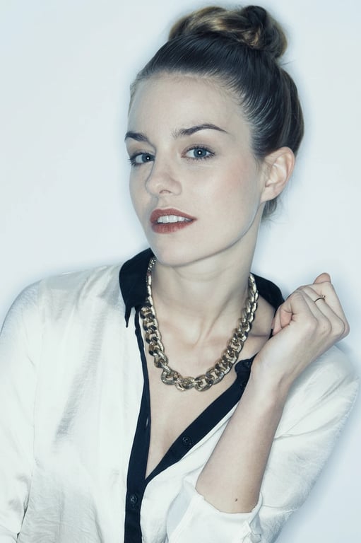 A cool aesthetic headshot of a woman, desaturated warm colors, emphasis on blues and greys, soft flat lighting, professional and sleek look.