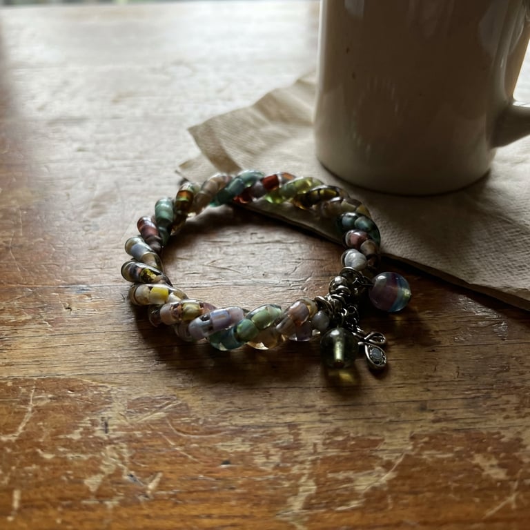 Place the bracelet on a beautiful female model’s neck. Capture a body shot with balanced proportions against a clean, light beige studio background. Employ high-fashion studio lighting with dramatic, directional light and deep shadows to accentuate the beauty product's texture, maintaining a clean, uncluttered aesthetic, and add a subtle shimmer to her collarbone.