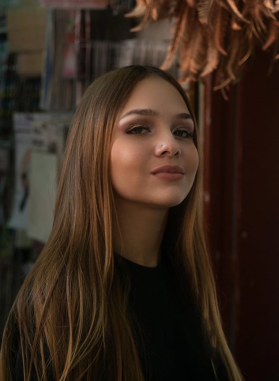 Extend the original woman portrait into a full-body image with minimal alteration. Maintain the same person, clothing, and scene, focusing only on proportionally accurate body completion, realistic leg placement, and seamless visual continuity without introducing new styling or background changes.