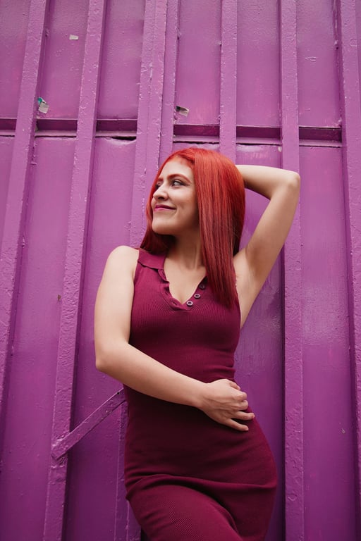 a portrait of a woman in a long cardigan and boots, posing by a wooden fence with fall foliage background
