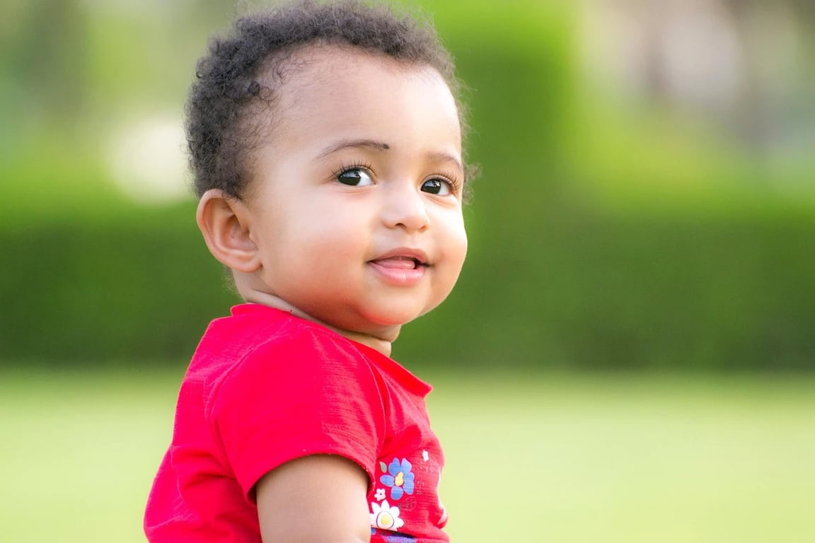 AI green screen remover before photo - child in red shirt smiling on green field background