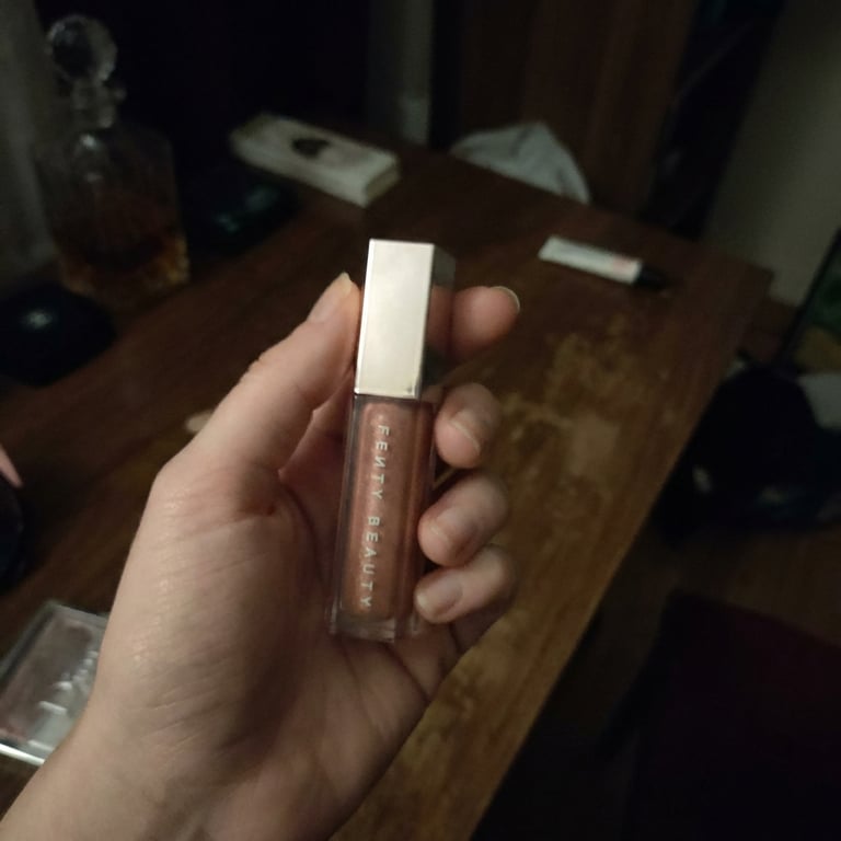 Refine the lipstick image into a dramatic studio shot with sophisticated lighting, deep shadows, and a luxurious vanity background, highlighting the product's form and intricate textures.