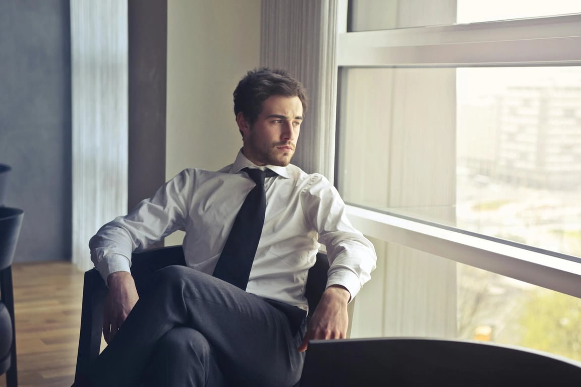 A high contrast portrait of a man, intense shadow detail, glowing highlights on skin and hair, sharp clarity, urban background with hard lines.