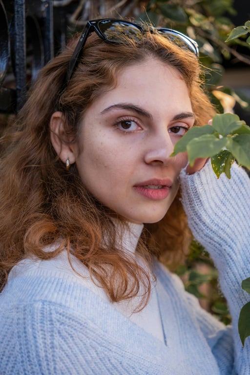 Reconstruct a full-body portrait of the woman by filling in the missing lower body while keeping the original pose, outfit, and background intact. Ensure realistic anatomy, natural weight distribution, and correct body mechanics so the completed image appears as a single uninterrupted photograph.