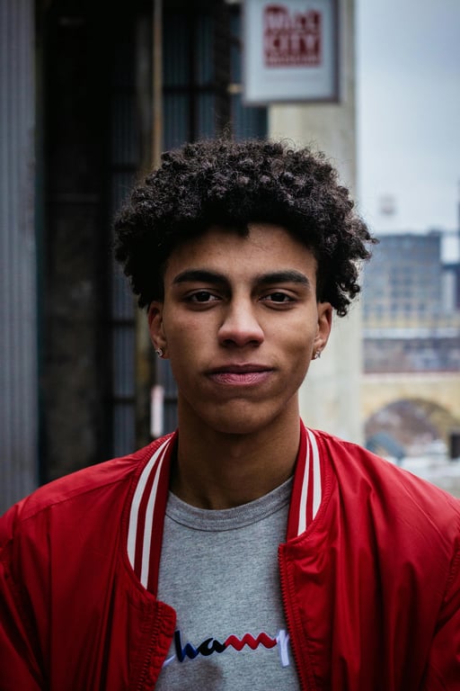 A cool-toned environmental portrait of a man, harmony between cool subject lighting and neutral background, desaturated greenery, overcast sky ambiance.