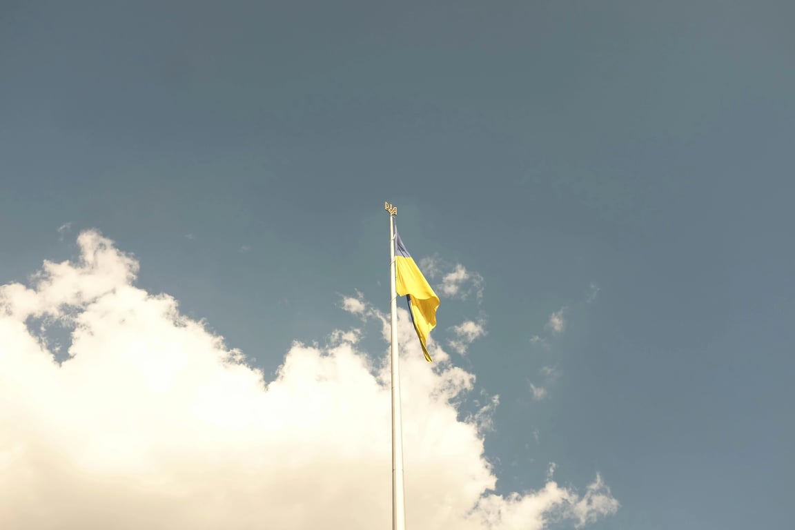 A progressive rainbow flag with additional intersecting stripes representing solidarity, incorporating symbolic icons (hands, olive branches) in a central vertical panel.