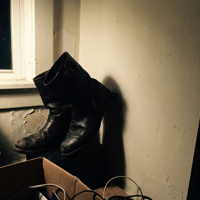 Refine the boot into an artistic studio showcase with soft, atmospheric lighting, gentle shadows, and a minimalist, textured abstract background, emphasizing the product's form and intricate textures.