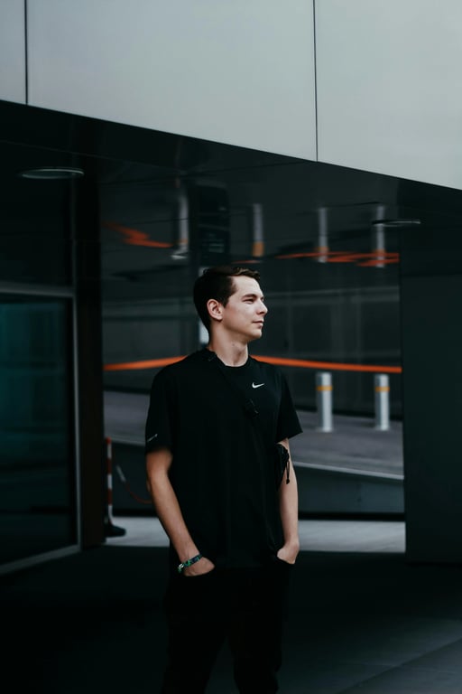 a portrait of a person wearing refined Korean minimalist menswear with a straight tailored silhouette, relaxed shoulder line, clean-cut jacket and trousers, smooth woven fabric, restrained detailing, balanced proportions, composed standing pose, gentle daylight atmosphere