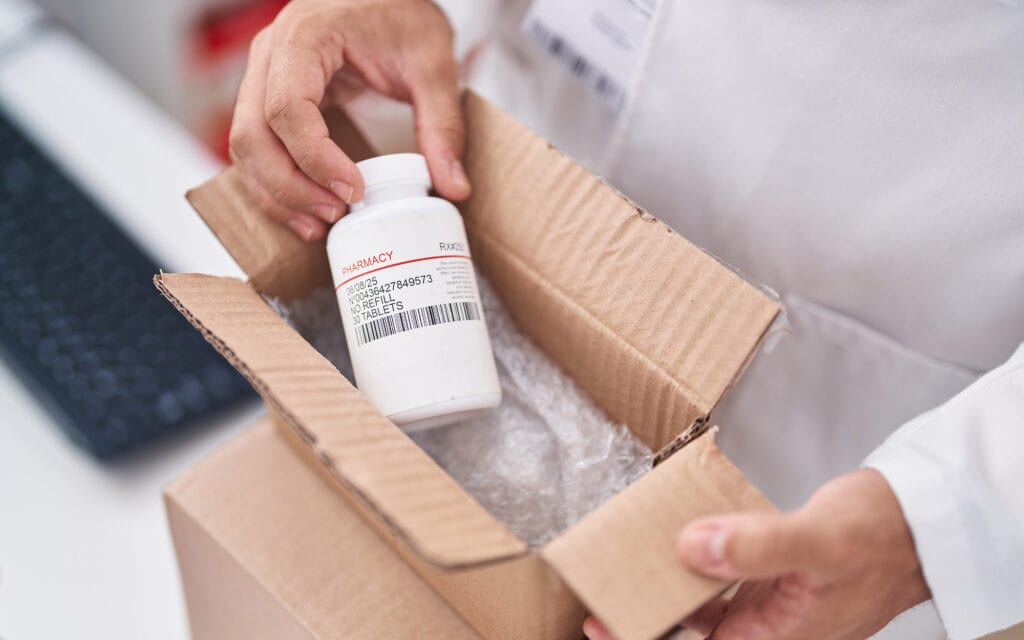 Pharmaceutical bottle being packed for protected shipment
