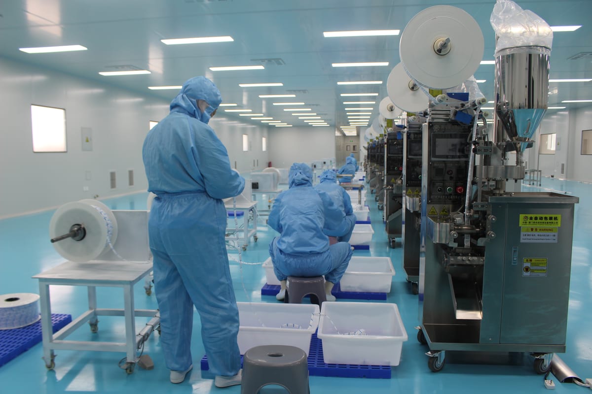 Operators working beside desiccant packing equipment in a cleanroom