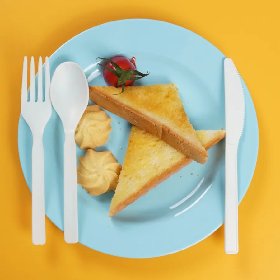 White CPLA cutlery arranged around a plated hot-food meal