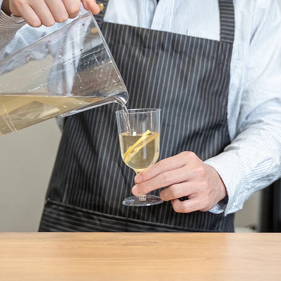 A cold beverage being poured into clear drinkware for service
