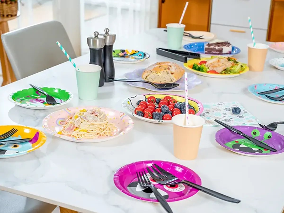 Event table laid with disposable plates, cups, and cutlery as a coordinated catering place setting