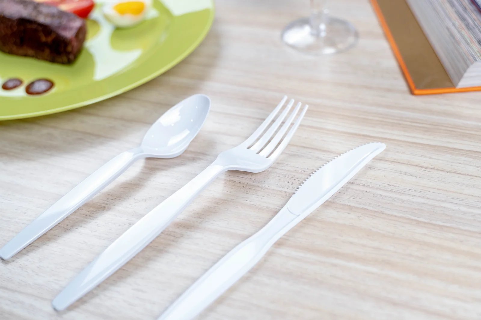 White disposable cutlery arranged beside a plated meal
