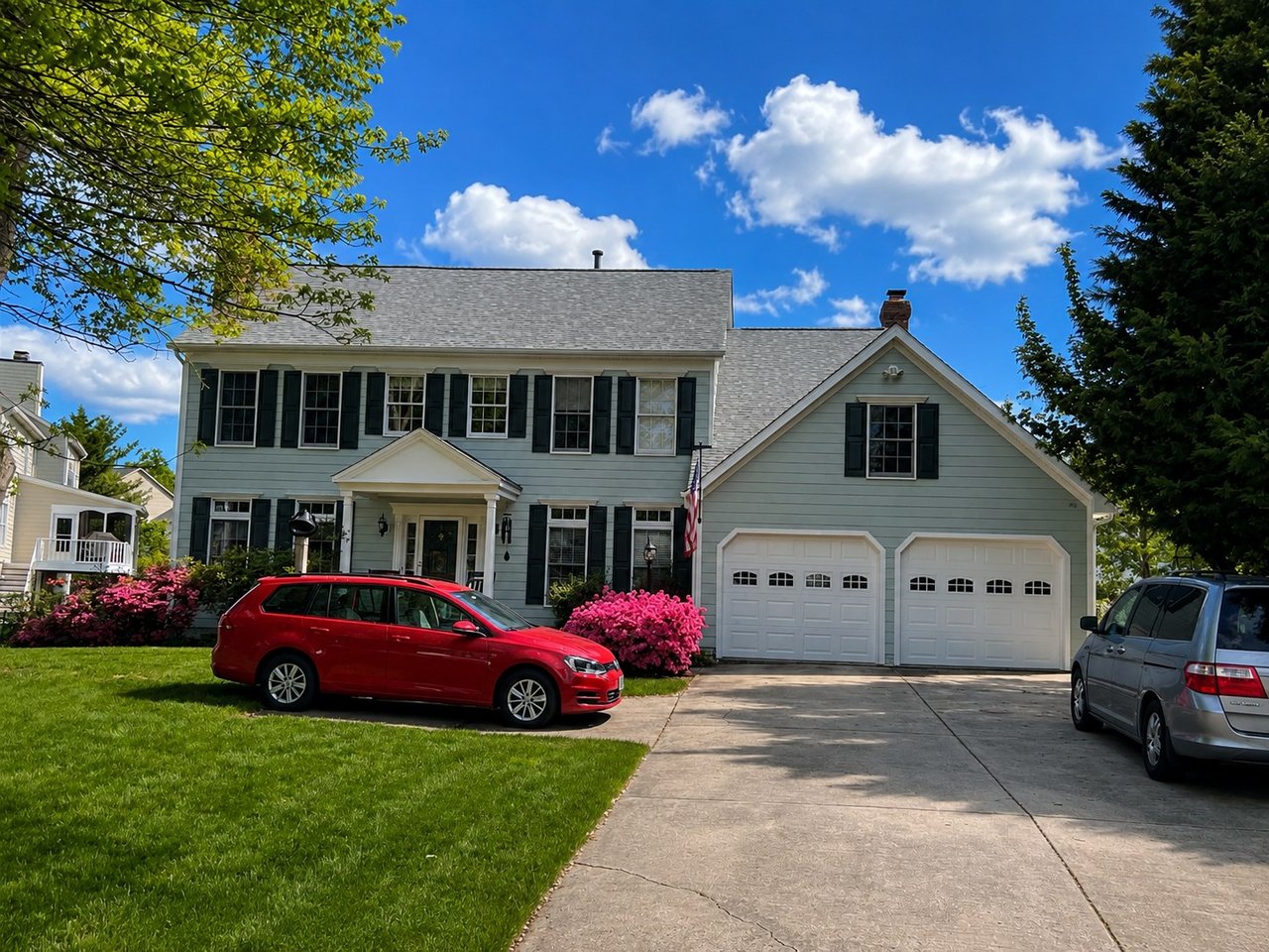 Sage green siding, black shutters and white garage doors on a colonial home in the DMV area