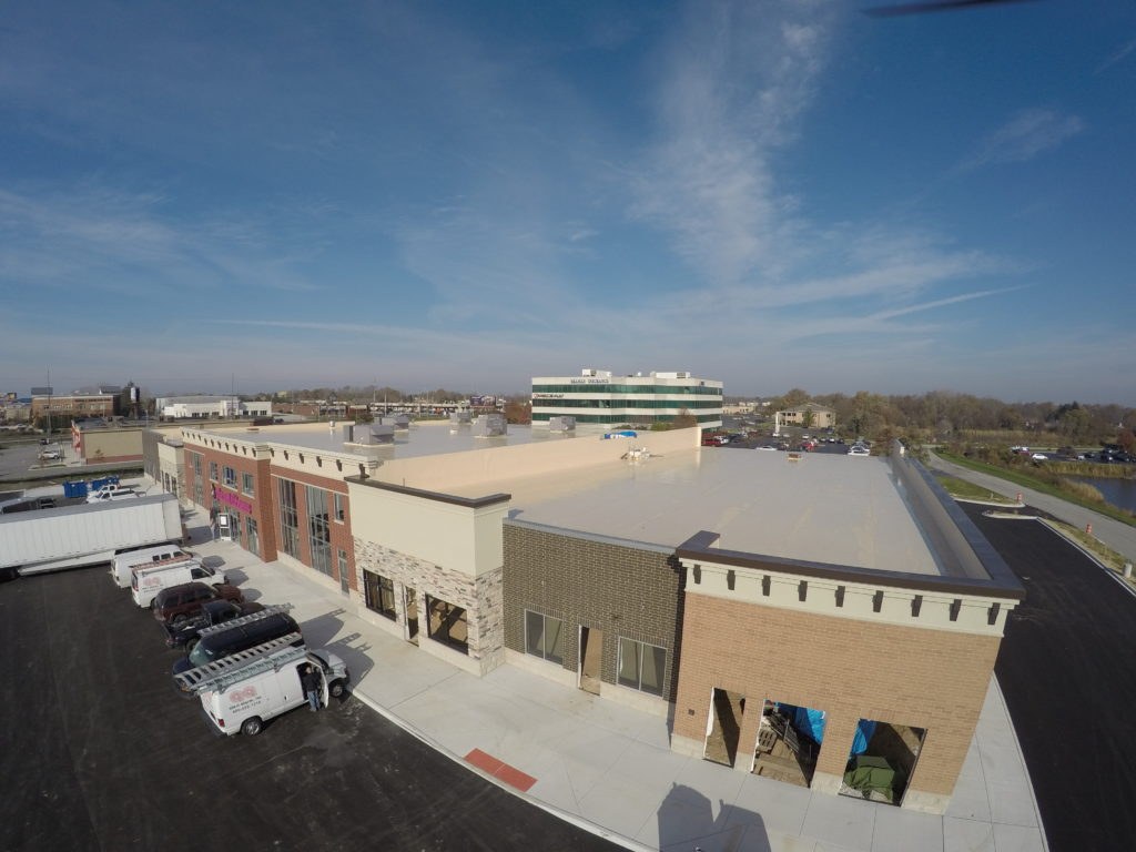 Aerial view of a completed commercial flat roof installation with DMV Exteriors service vans on site