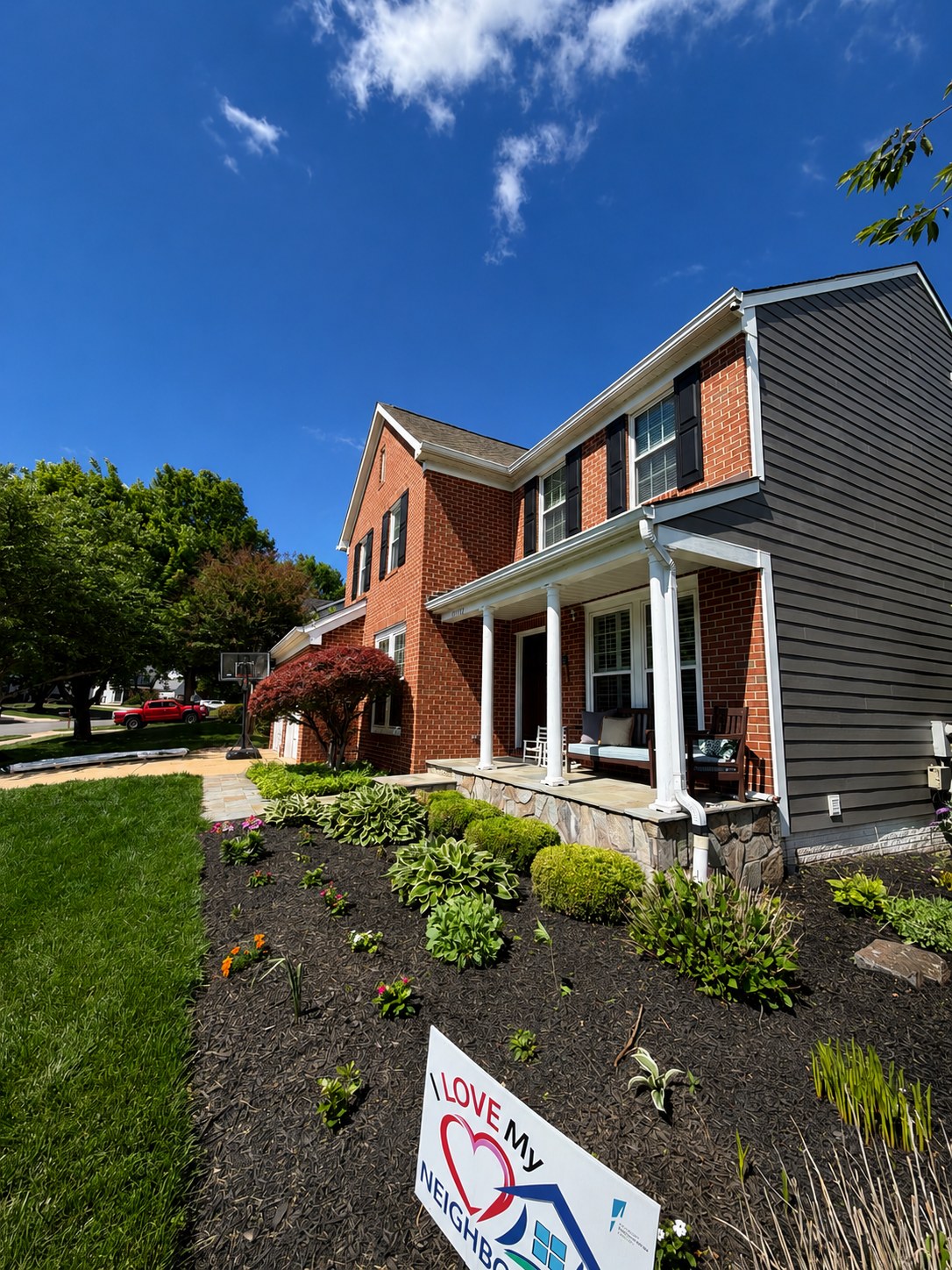 Red brick colonial with a dark gray siding gable end, new white trim and gutters