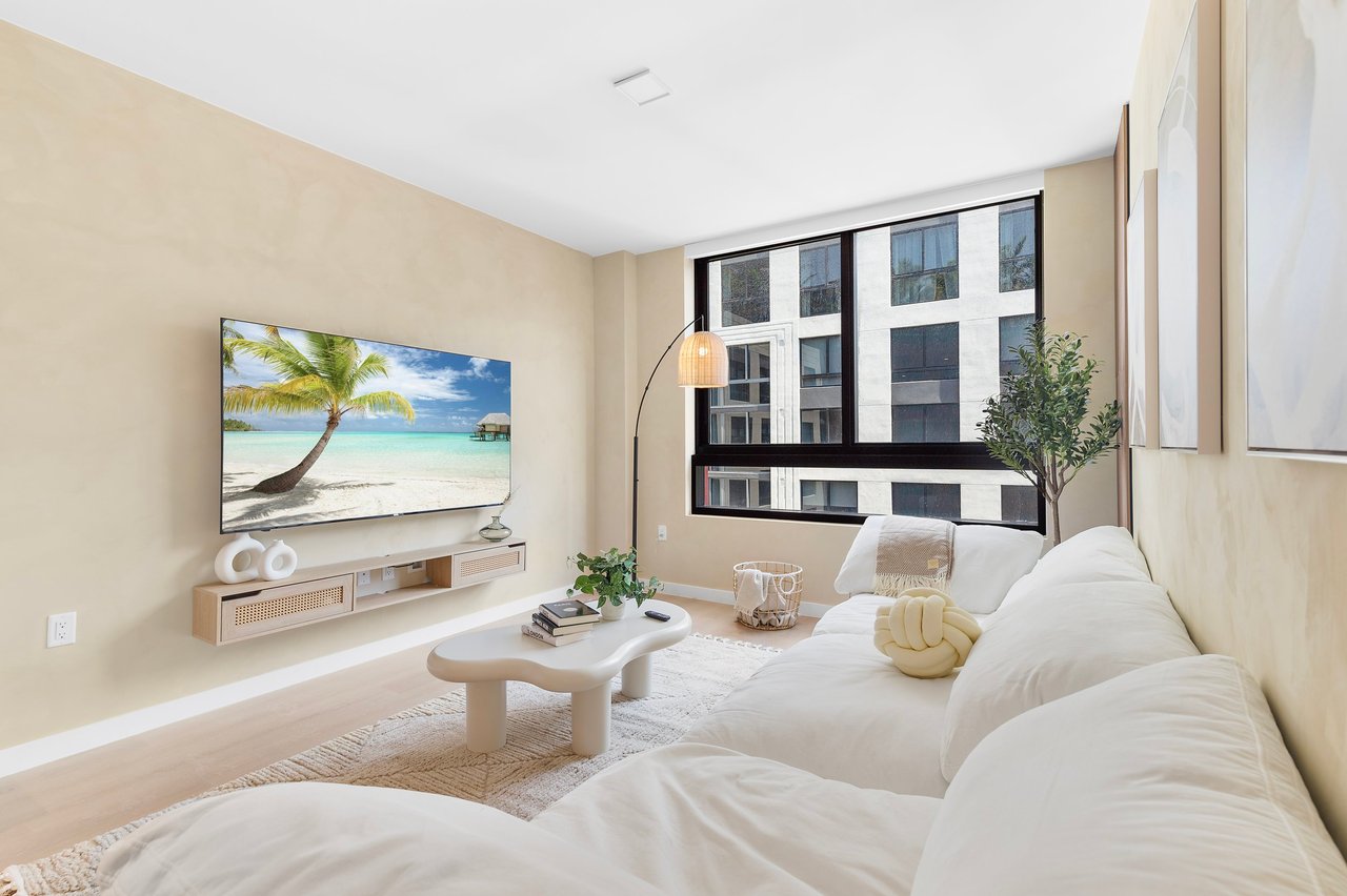 Bright living room with a white sofa, wall-mounted TV, floor lamp and a large window
