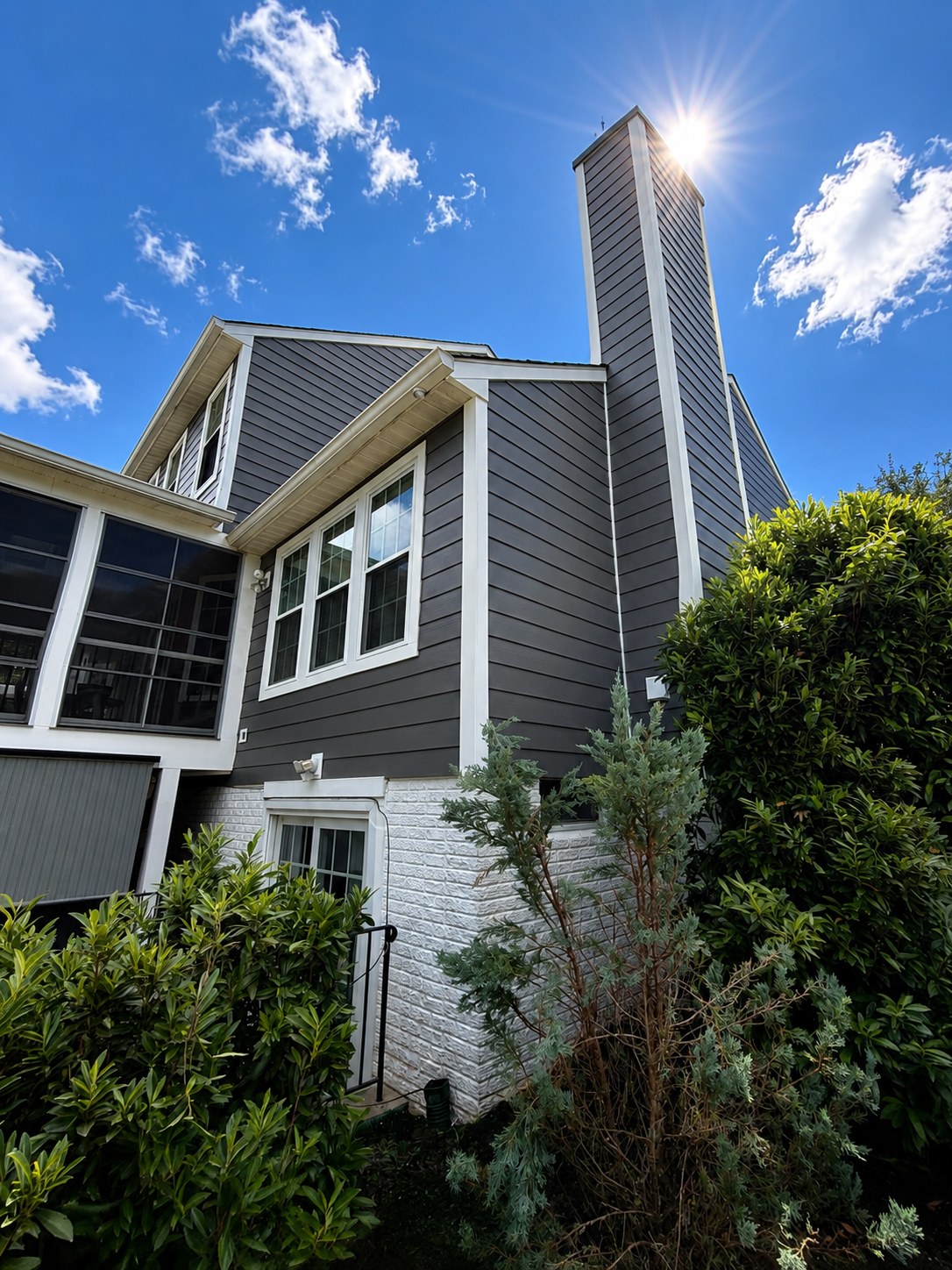 Dark charcoal lap siding and white trim with a tall chimney chase, installed by DMV Exteriors & Restorations