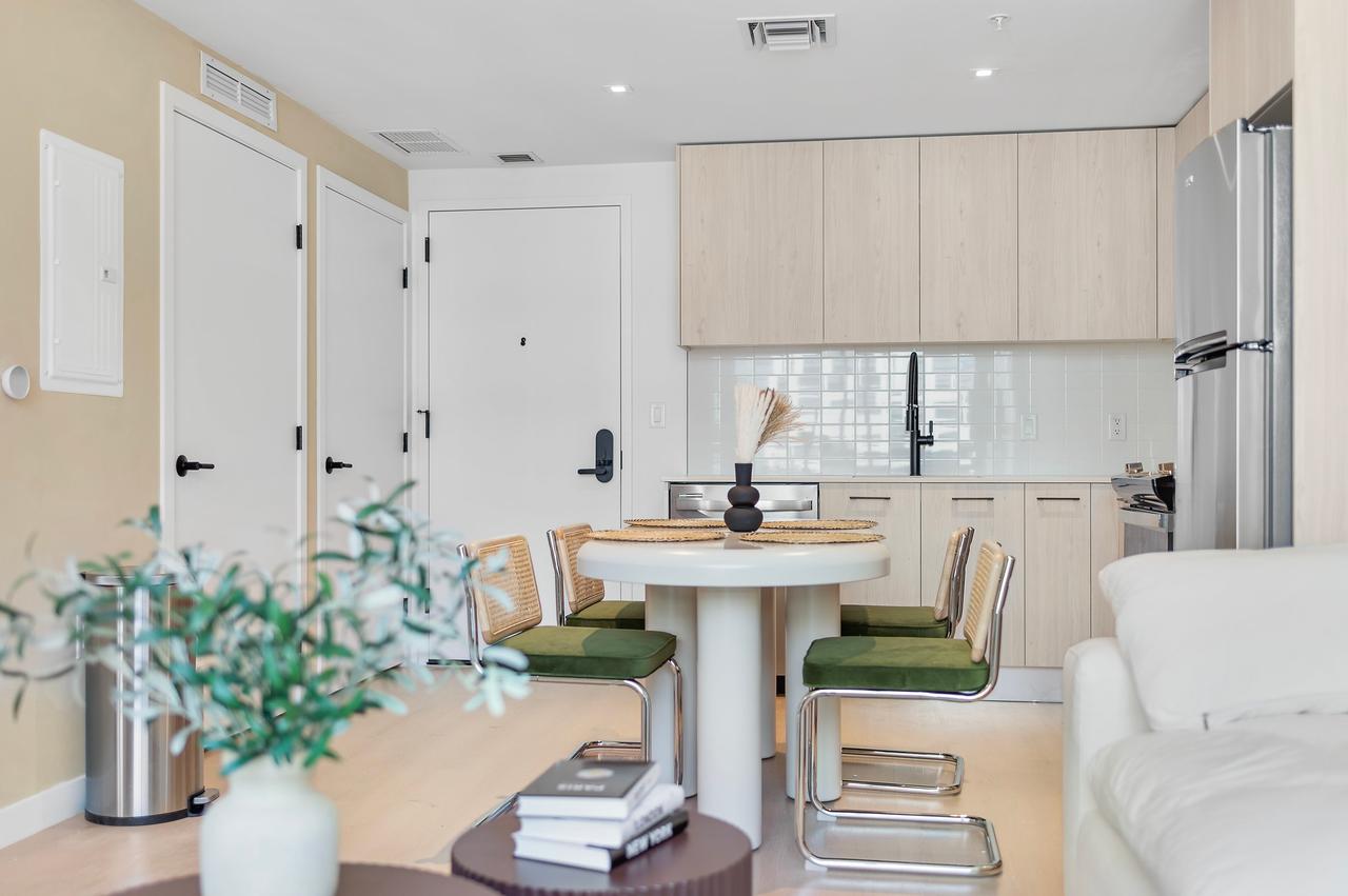 Kitchen and dining area with a round white table, green chairs and beige cabinetry