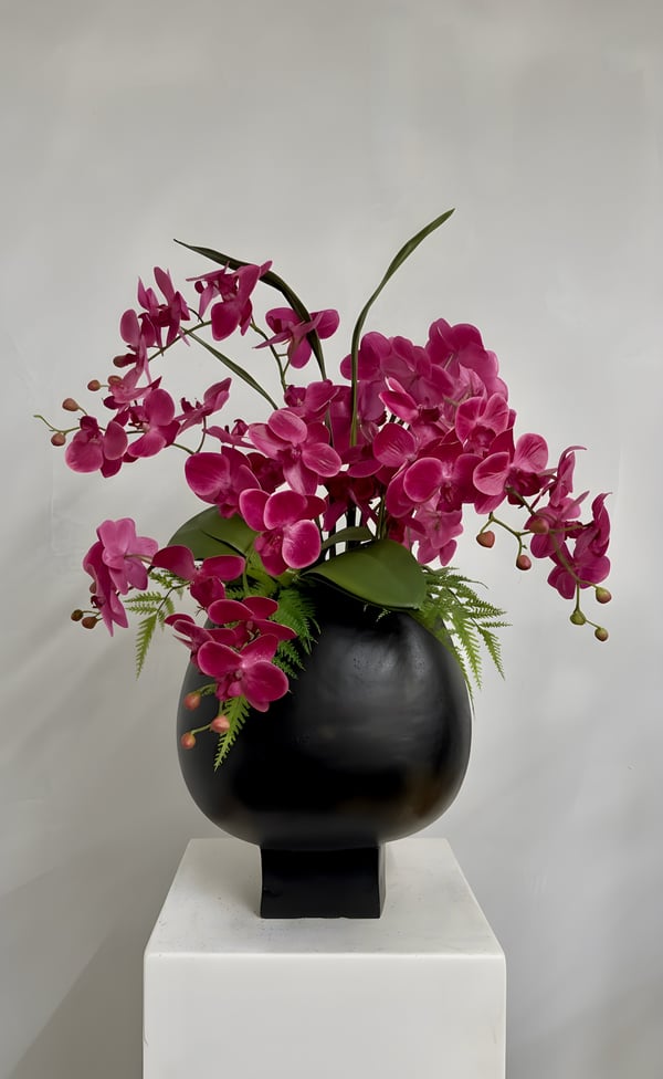 Handcrafted luxury hot pink real touch orchid arrangement in a contemporary black footed aluminium vase. One-of-a-kind bespoke faux floral design created exclusively by Demmerys.