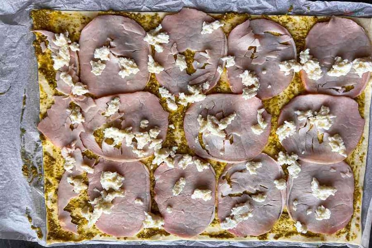 Ciasto francuskie posmarowane pesto bazyliowym, z szynką oraz mozzarellą.