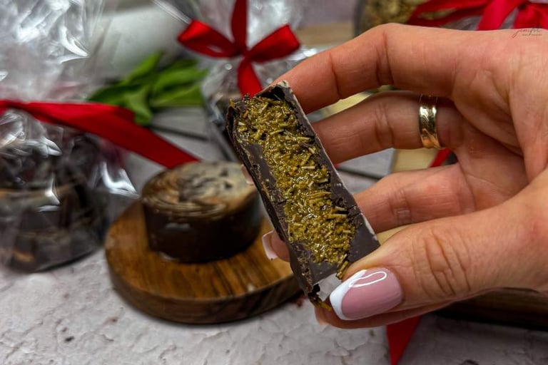 Dubajska czekolada trzymana w dłoni, w tle widoczne czerwone kokardki