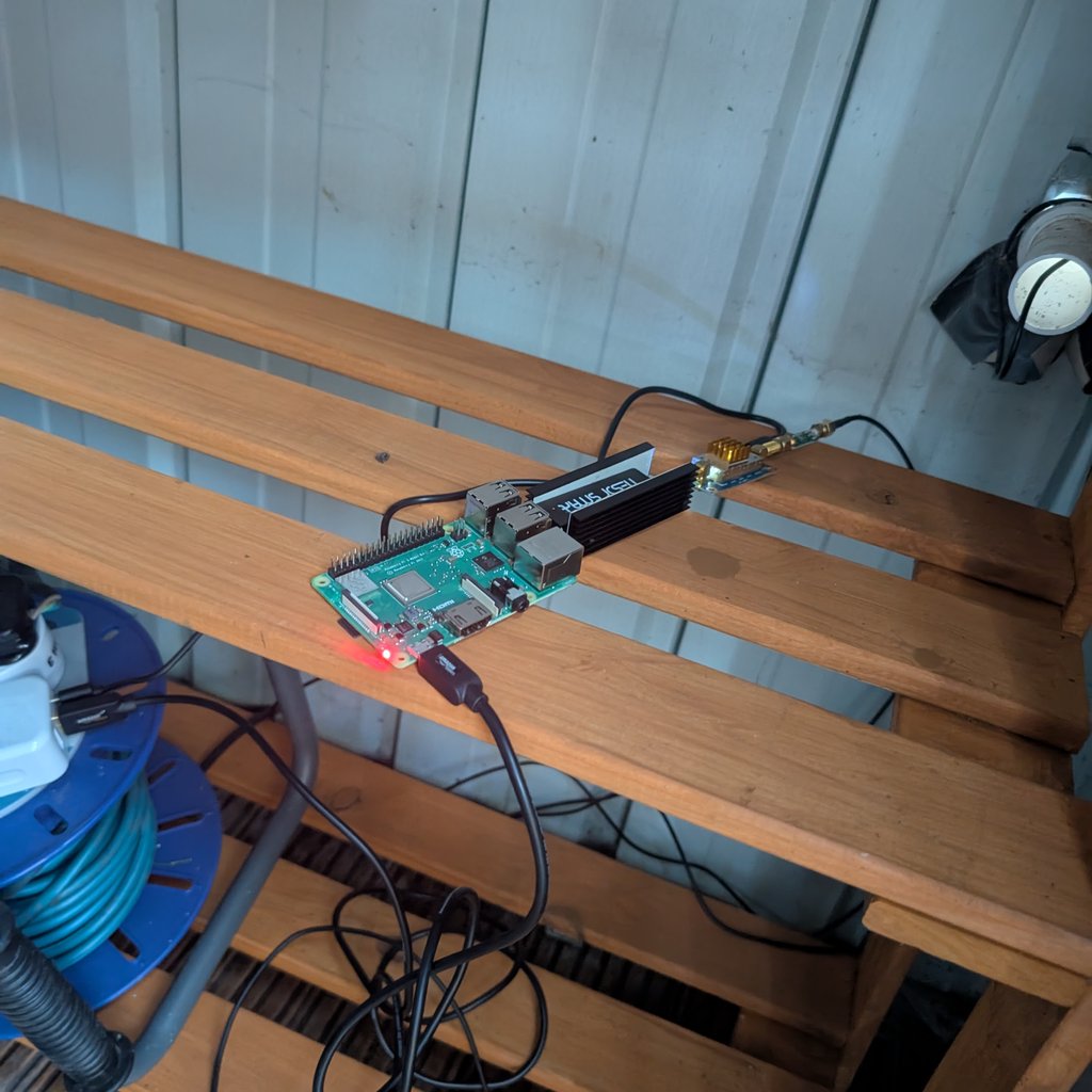 A Raspberry Pi 3B+ sitting on a shelf in a small metal shed, with an SDR device plugged into it.