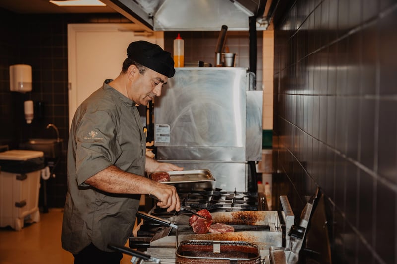 Chef-kok grilt vlees in de open keuken