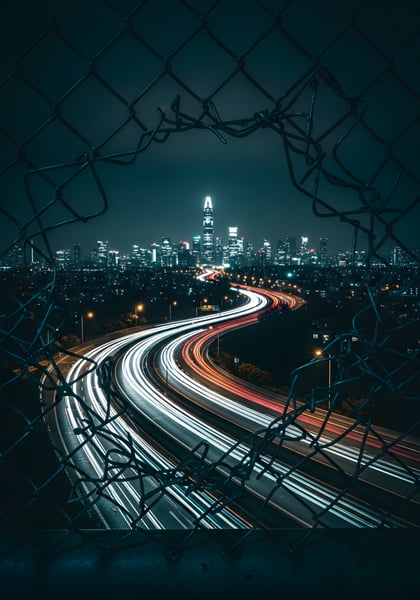 Uma cidade de noite com uma cerca de metal aberta 01