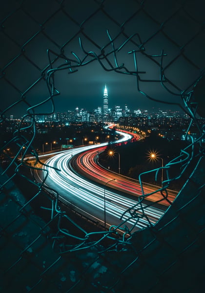 Uma cidade de noite com uma cerca de metal aberta 03
