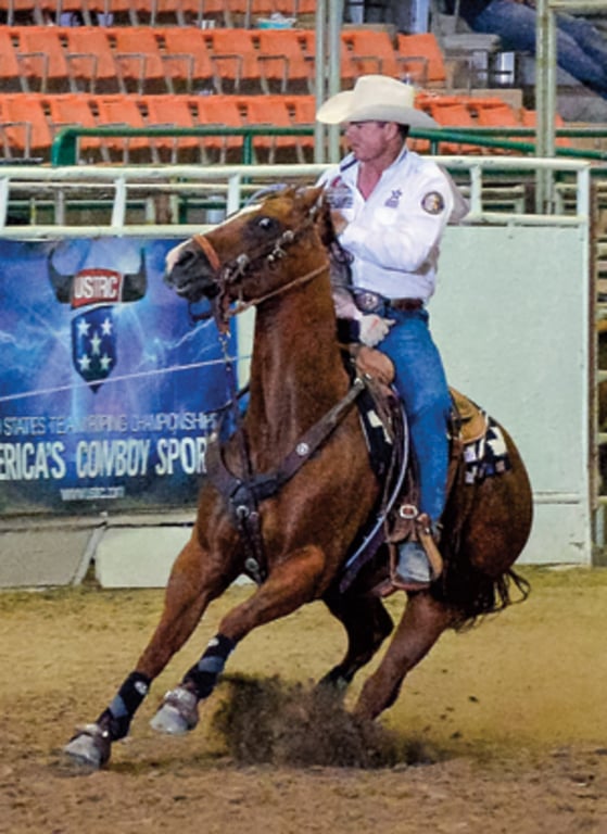 Chris Cox on horseback at a USTRC team roping competition — showing his versatility across western disciplines