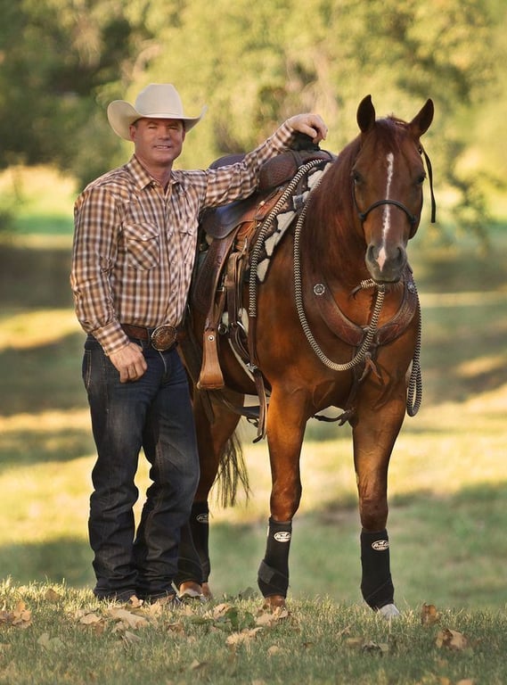 Chris Cox standing with a saddled chestnut horse — clinician and horsemanship educator
