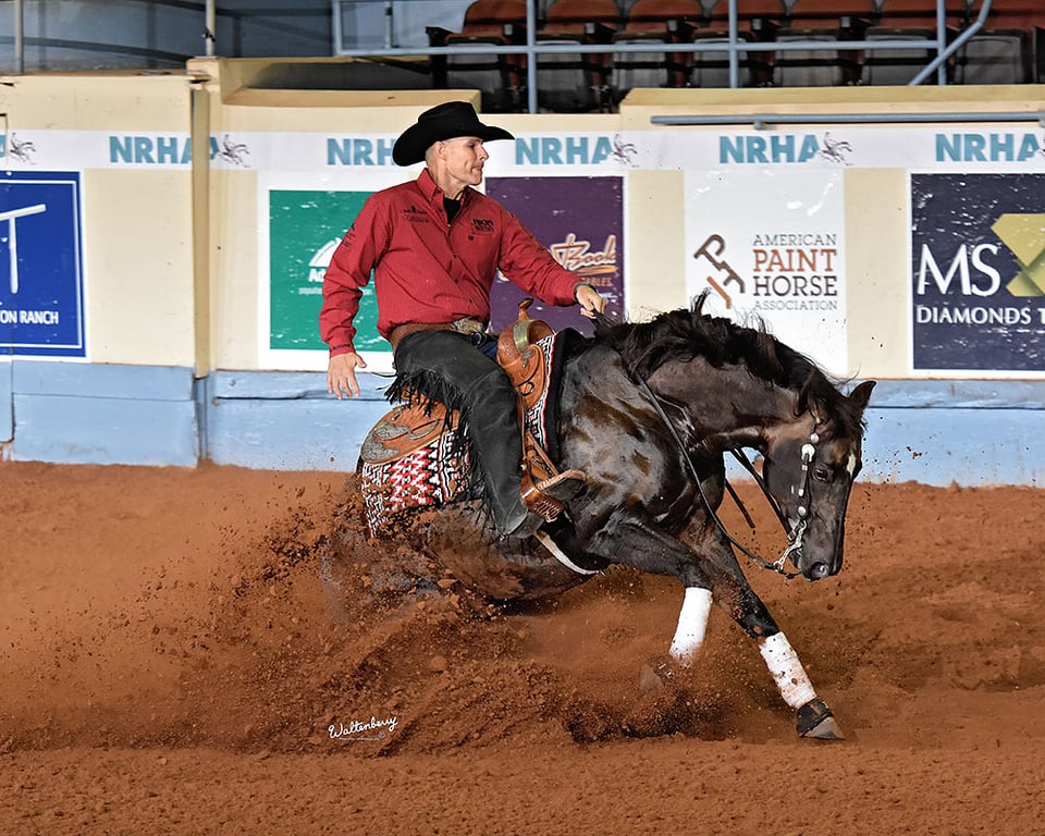 Jason Vanlandingham on a black horse executing a sliding stop at the NRHA Futurity