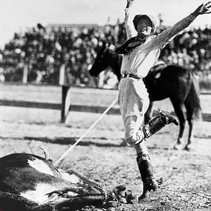 Mabel Strickland Woodward in rodeo competition — early twentieth century action shot with packed arena crowd