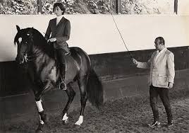 Nuno Oliveira teaching a student — longeing a rider on a black horse in the arena