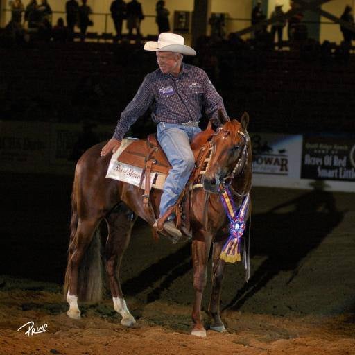 Ted Robinson aboard a winning horse at an NRCHA competition, championship ribbon displayed