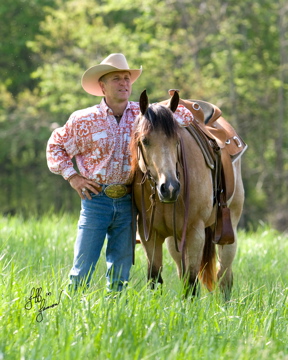 Tommy Garland standing with a buckskin horse in a green field — Garland's Training Center