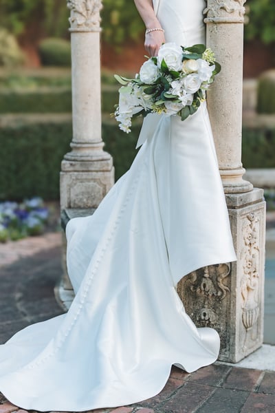 Bride in mermaid gown standing under weeping willow branches by the lake at golden hour, gazing across the water