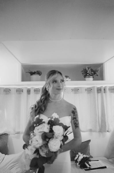 Bride alone inside the vintage Airstream holding her bouquet and looking off to the side