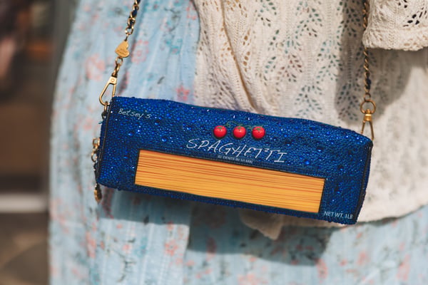 Close-up of a guest's blue glitter Betsey Johnson spaghetti-box novelty clutch purse