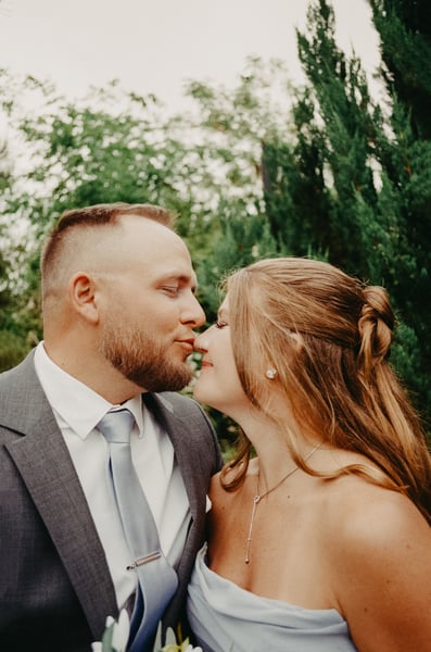 Couple sharing a tender kiss, man in gray suit with blue tie, woman in silver strapless gown