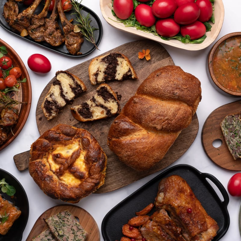 Sunt sigura ca te regasesti si tu in povestea mea de familie: mergem acasa de sarbatori, pregatim diverse preparate traditionale, ne agitam, uneori chiar ne certam pe tema “cum se taie corect gogosarul pentru salata boeuf?”. Pana sa ajungem sa ne asezam la masa, deja suntem obositi si vrem sa treaca totul mai repede, ca sa revenim la “normal”. In special mama e intotdeauna cea mai obosita, pentru ca ea s-a asigurat, ca de obicei, ca avem de toate de pus pe masa si ca toata lumea e fericita.Dar in zilele noastre pline si agitate, oare chiar mai are sens sa ne obosim cateva zile cu gatitul cand am putea avea fara efort intregul meniu pe masa? Atunci cand am aflat despre Bucate pe Roate am fost fascinata: este o firma de catering care iti livreaza acasa intregul meniu de Paste! Tu nu mai trebuie decat sa te bucuri de cei dragi, pentru ca masa de Paste este asigurata – plina de bunatati traditionale gatite cu grija si generozitate de cei de la Bucate pe Roate.Meniul de Paste 2025 de la Bucate pe RoateMereu am fost surprinsa placut de cat de gustoasa si autentica este mancare preparata de cei de la Bucate pe Roate: chiar are acel gust “de acasa” si se simte ca este gatita cu drag si rabdare. Meniul de Paste de anul acesta este gandit pentru mese in familie si este ideal pentru cei care vor sa se bucure de masa de Paste fara efort, dar cu gust autentic si calitate garantata.Meniul include preparate clasice precum:Cozonacul de Paste este vedeta sezonului: framantat manual, fara premixuri sau aditivi, umplut generos cu nuca, cacao si rahat.