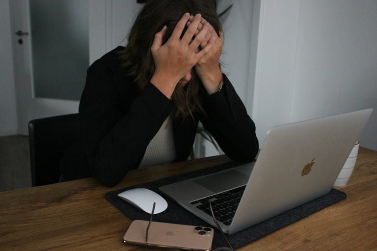 Stressed woman holding her head while working on a laptop at home office