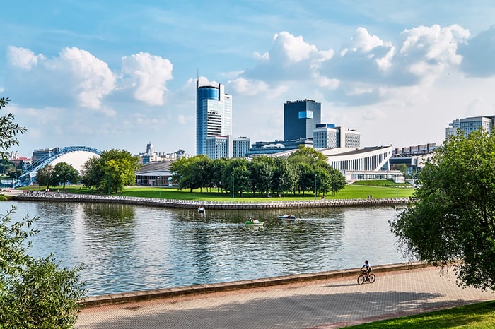 A picturesque scene of individuals sitting on a park bench near a river in a green smart city