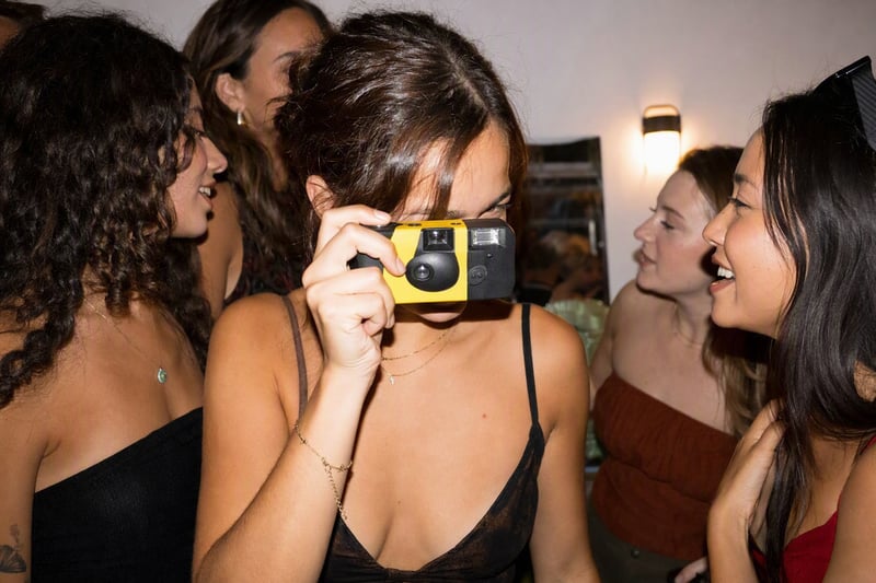 A flash photo of friends at a table at night, bright faces and a background falling to black