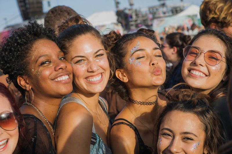 A festival crowd with arms raised at sunset, dust in the air above the stage