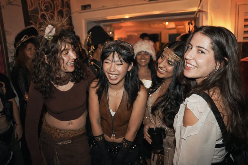 A group in coordinated costumes lit by flash on a dark street lined with pumpkins